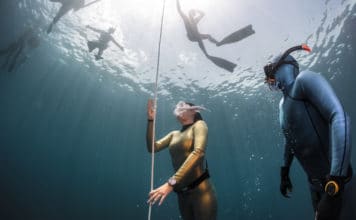 Lady free diver ascending along the rope in the depth