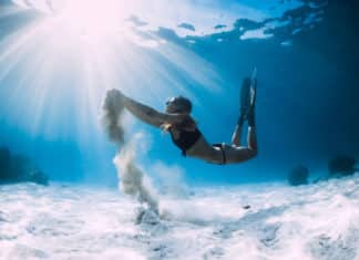Woman freediver with white sand over sandy sea with fins. Freediving underwater in ocean